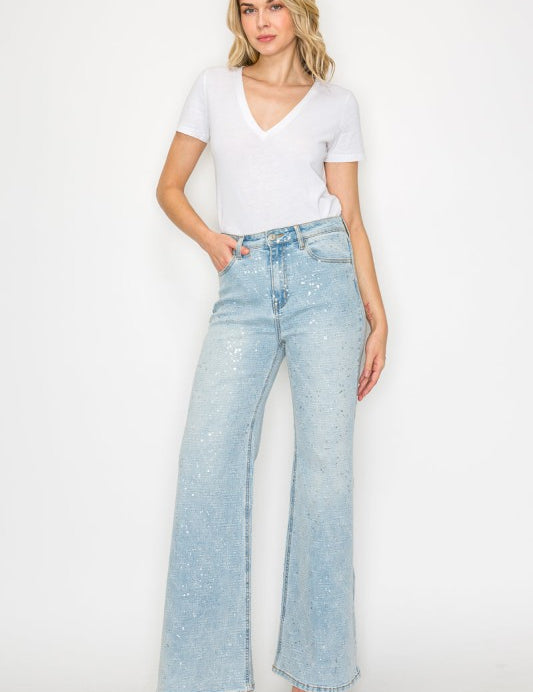 Woman wearing a white t-shirt and light blue metallic finish jeans on a white background