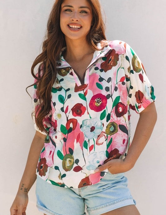 Woman wearing a colorful, floral short-sleeve blouse against a white background