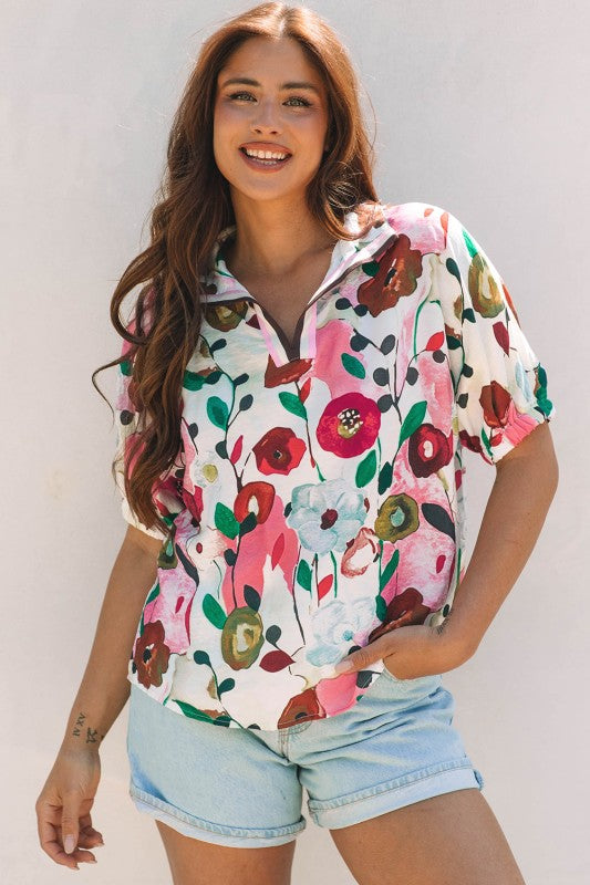 Woman wearing a colorful, floral short-sleeve blouse against a white background